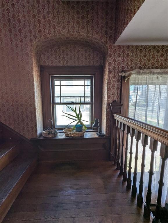 staircase with wallpapered walls, wood-type flooring, and plenty of natural light