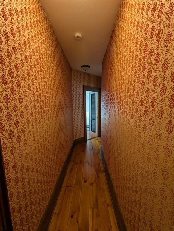hallway featuring hardwood / wood-style floors and wallpapered walls