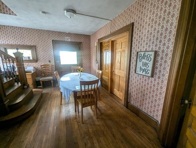 dining area with dark wood-type flooring, stairway, and wallpapered walls