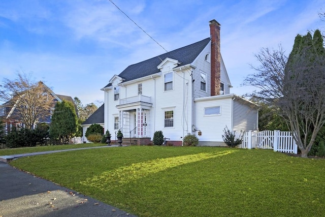 view of front facade featuring a balcony and a front yard