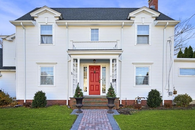 view of front facade with a front lawn and a balcony