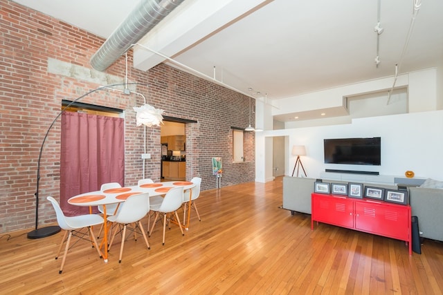 dining room with brick wall, a high ceiling, and hardwood / wood-style floors