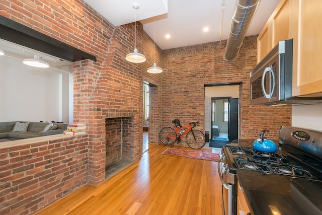 interior space featuring light wood-style floors, a towering ceiling, brick wall, and a fireplace