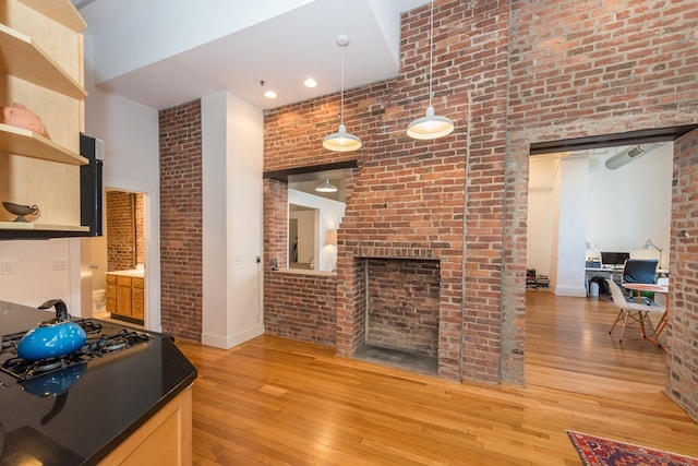 living room featuring baseboards, light wood-style flooring, a high ceiling, and brick wall