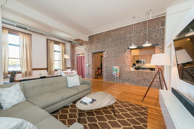 living area featuring brick wall and wood finished floors