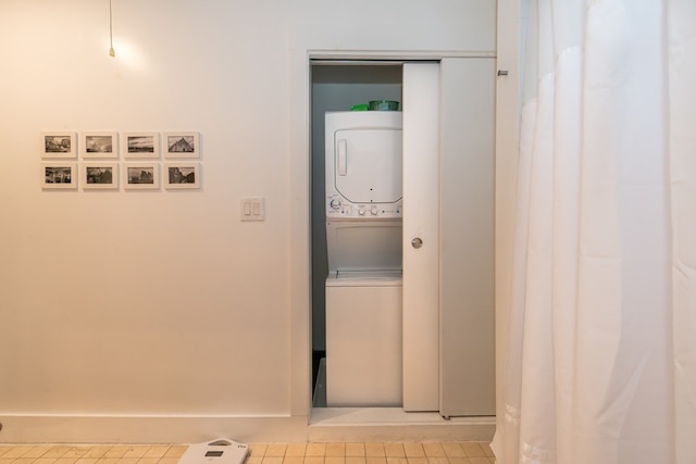 clothes washing area featuring stacked washer / drying machine, tile patterned floors, and laundry area