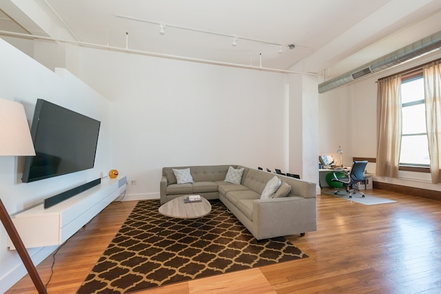 living area featuring baseboards, rail lighting, light wood-style flooring, and visible vents