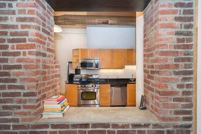kitchen with brick wall, appliances with stainless steel finishes, and visible vents