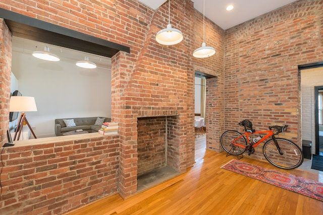 living room with brick wall, a high ceiling, a brick fireplace, and hardwood / wood-style floors