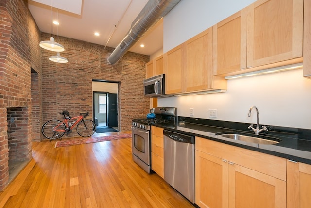 kitchen with light brown cabinetry, stainless steel appliances, and brick wall