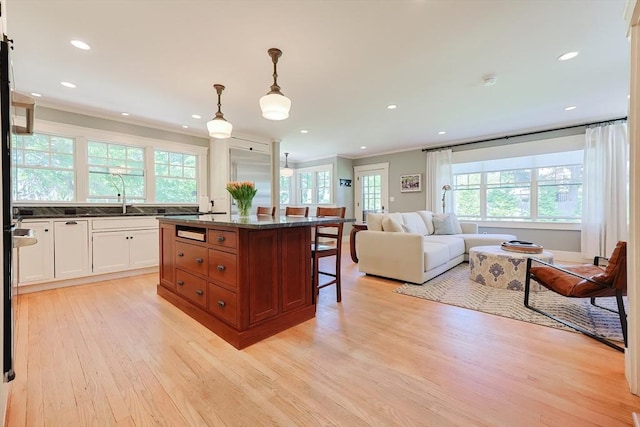 5 Baxter St, Westborough, MA 01581 - kitchen featuring light wood-style floors, a breakfast bar, white cabinetry, a kitchen island, and a sink