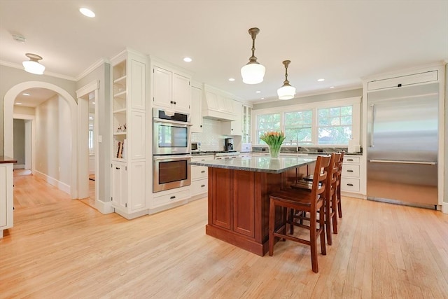 5 Baxter St, Westborough, MA 01581 - kitchen featuring appliances with stainless steel finishes, ornamental molding, arched walkways, light wood-type flooring, and open shelves