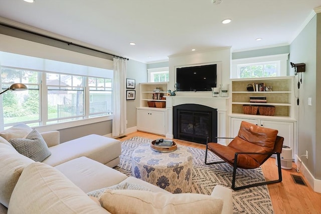 5 Baxter St, Westborough, MA 01581 - living area with crown molding, light wood-style flooring, a glass covered fireplace, baseboards, and recessed lighting