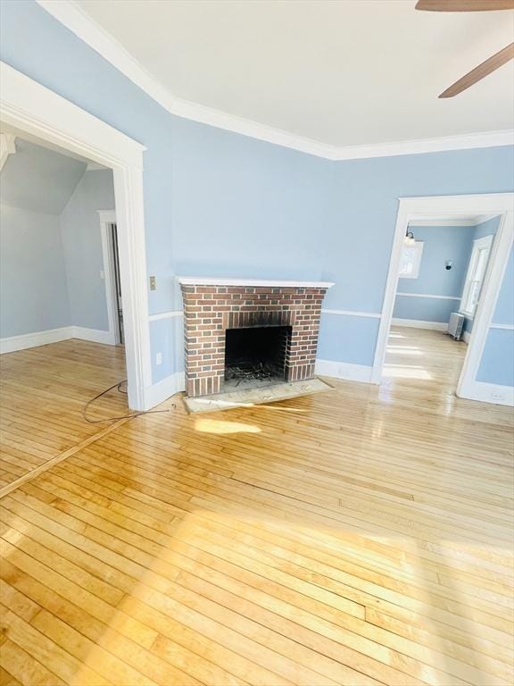 unfurnished living room with crown molding, ceiling fan, a fireplace, and light hardwood / wood-style floors