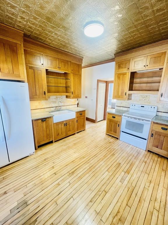 kitchen featuring crown molding, sink, white appliances, and light hardwood / wood-style flooring