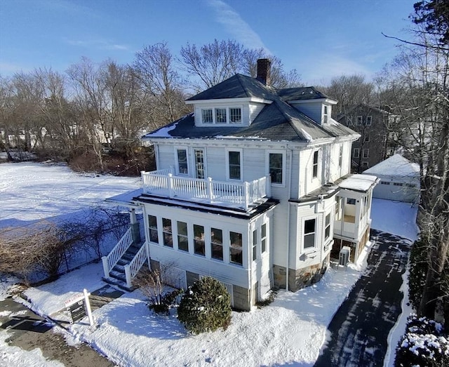 snow covered rear of property with central AC unit and a balcony