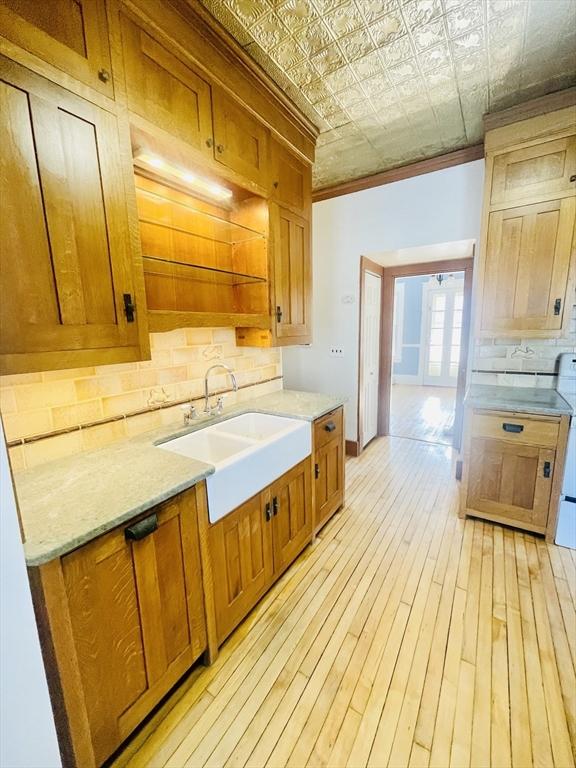 kitchen with sink, decorative backsplash, ornamental molding, and light wood-type flooring