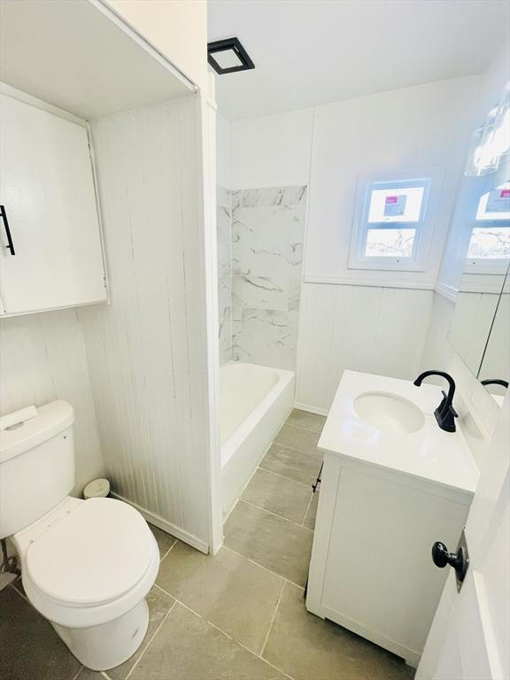 full bathroom featuring tiled shower / bath, vanity, and toilet