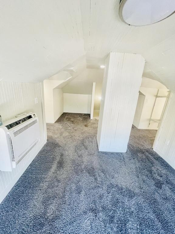 additional living space with heating unit, lofted ceiling, and carpet flooring