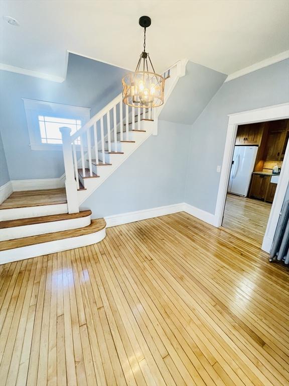 staircase featuring crown molding, hardwood / wood-style floors, and a notable chandelier