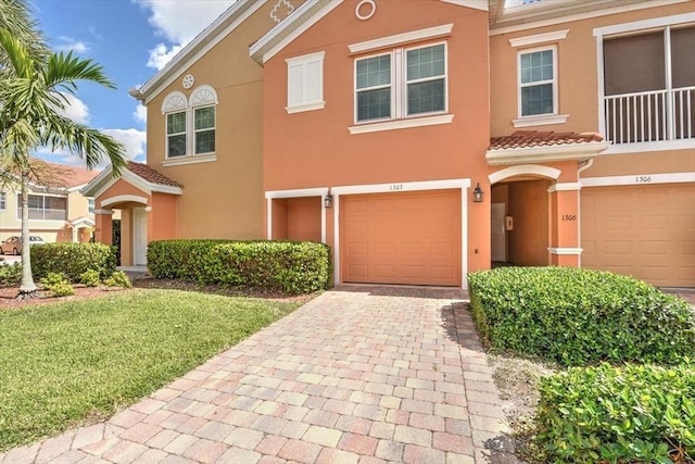 view of front of property featuring a garage, a tile roof, decorative driveway, and stucco siding