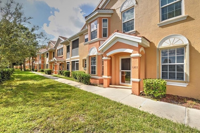 view of front facade featuring a front yard, a residential view, and stucco siding