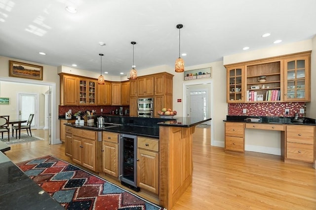 kitchen featuring stainless steel double oven, beverage cooler, pendant lighting, a center island, and light hardwood / wood-style floors