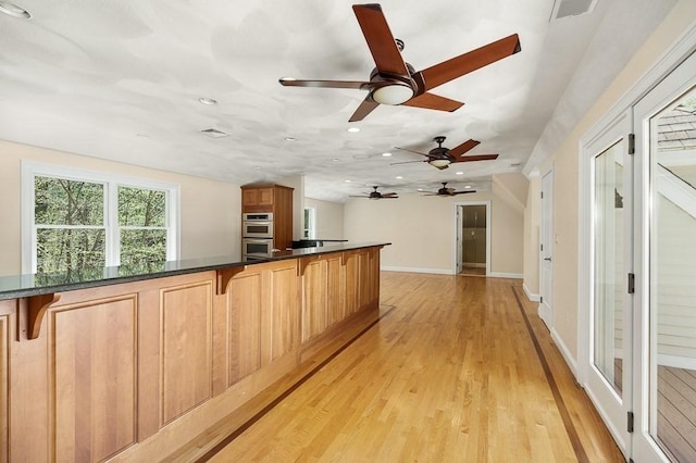 kitchen featuring lofted ceiling, light wood-type flooring, a breakfast bar area, and double oven