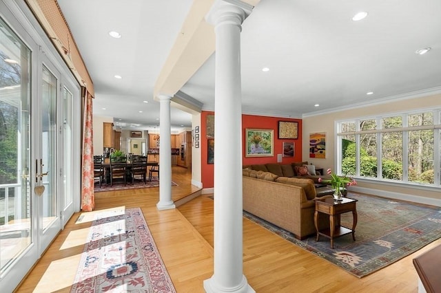 living room with light hardwood / wood-style flooring, ornate columns, ornamental molding, and french doors