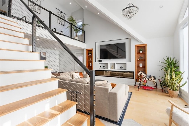 living room with a towering ceiling, a notable chandelier, and light hardwood / wood-style flooring