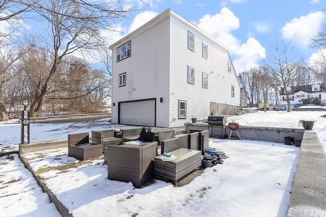 view of snow covered exterior with a garage and an outdoor living space