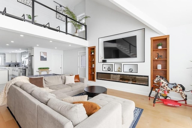 living room with a towering ceiling and light hardwood / wood-style flooring