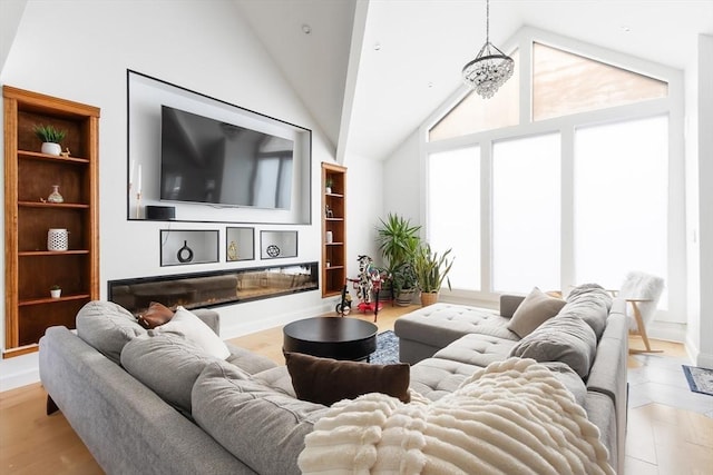 living room featuring built in features, a notable chandelier, and high vaulted ceiling