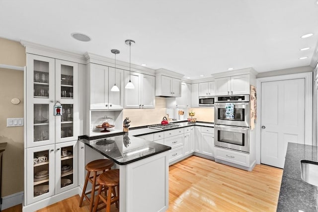 12 Braddock Park Unit 1, Boston, MA 02116 - kitchen with stainless steel appliances, decorative light fixtures, light wood-style flooring, glass insert cabinets, and backsplash