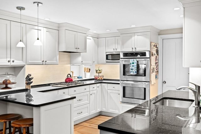 12 Braddock Park Unit 1, Boston, MA 02116 - kitchen featuring a sink, stainless steel appliances, tasteful backsplash, hanging light fixtures, and a breakfast bar area