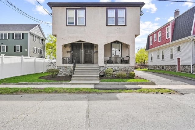 view of front of home featuring fence, stucco siding, and a porch