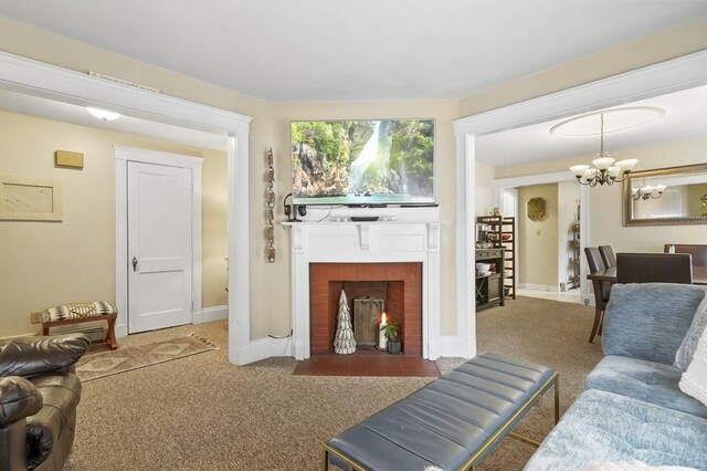carpeted living area featuring an inviting chandelier, baseboards, and a brick fireplace