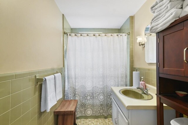 bathroom featuring a wainscoted wall, tile walls, curtained shower, and vanity