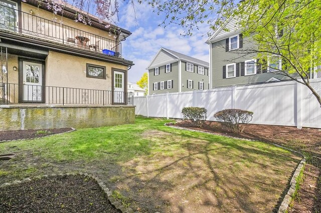 view of yard with a porch, fence, and a balcony