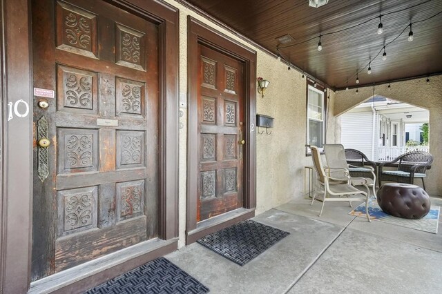 entrance to property featuring a porch and stucco siding