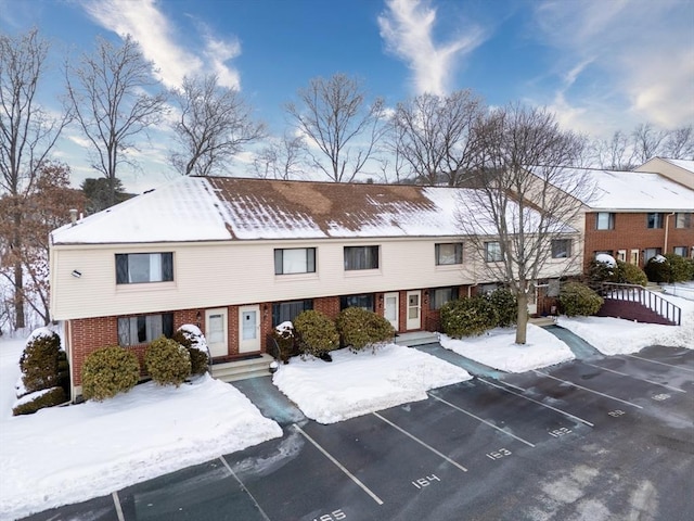 snow covered property featuring uncovered parking