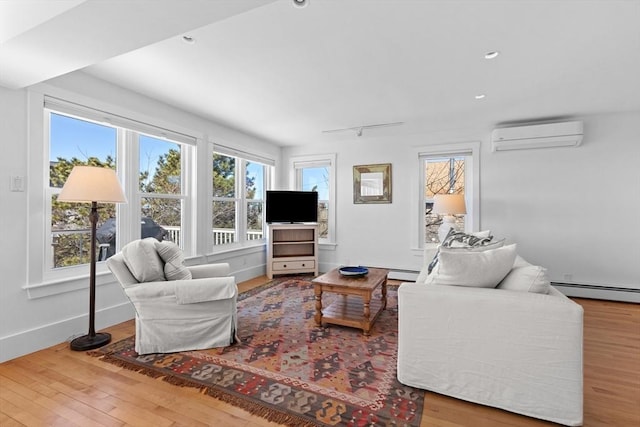 living area with hardwood / wood-style flooring, plenty of natural light, baseboards, and a wall mounted AC