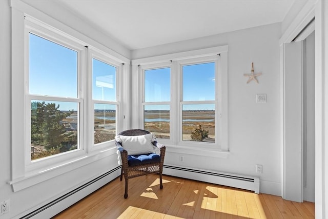 living area with a baseboard heating unit and light wood-style flooring