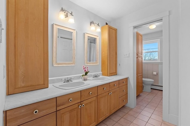 bathroom with double vanity, a baseboard radiator, a sink, and tile patterned flooring