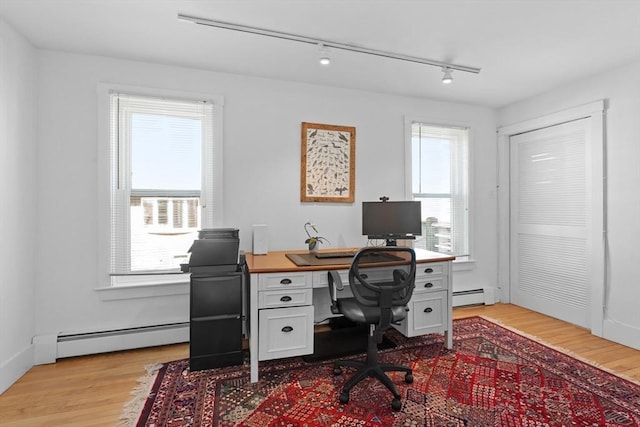 home office featuring light wood-type flooring, a wealth of natural light, and baseboard heating