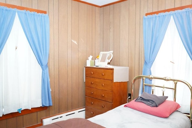 bedroom featuring a baseboard heating unit and wooden walls