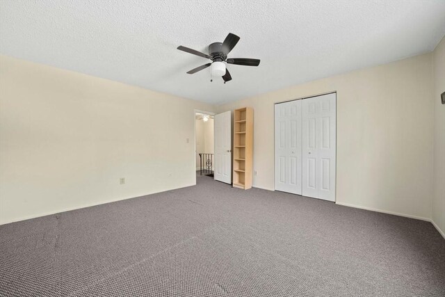 unfurnished bedroom with a textured ceiling, dark colored carpet, a ceiling fan, baseboards, and a closet