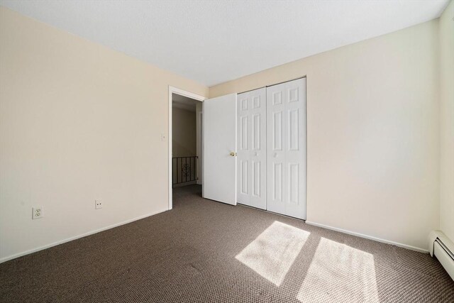 unfurnished bedroom featuring carpet floors, a baseboard radiator, and baseboards