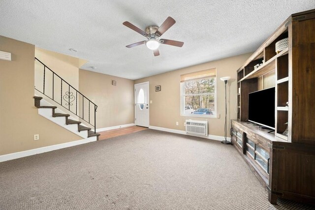 unfurnished living room with ceiling fan, a textured ceiling, a wall mounted air conditioner, carpet floors, and baseboards