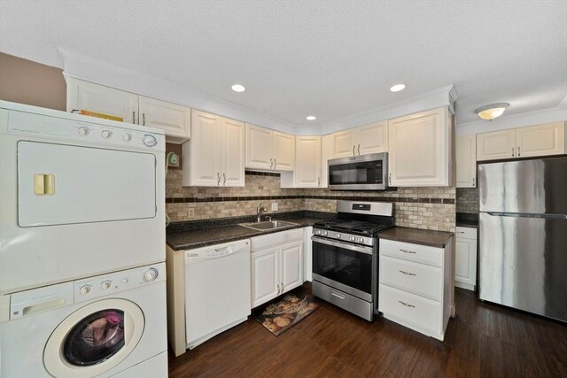 kitchen featuring stacked washer and clothes dryer, appliances with stainless steel finishes, backsplash, and dark countertops